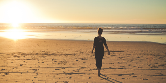 Woman walking along a beach at sunset, representing everyday comfort and effortless style