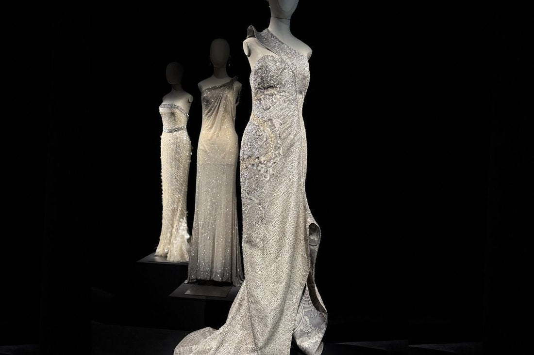 Three silver crystal and beaded one-shoulder gowns on mannequins displayed at the Giorgio Armani Privé 2005–2025 retrospective, Milan 2025