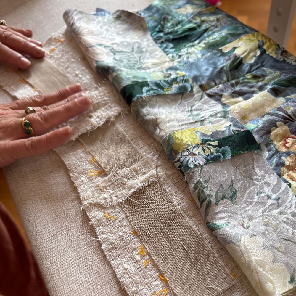 Hands pressing layered couture fabrics including tweed and floral brocade on a worktable — After Stilettos French Couture Jacket Technique