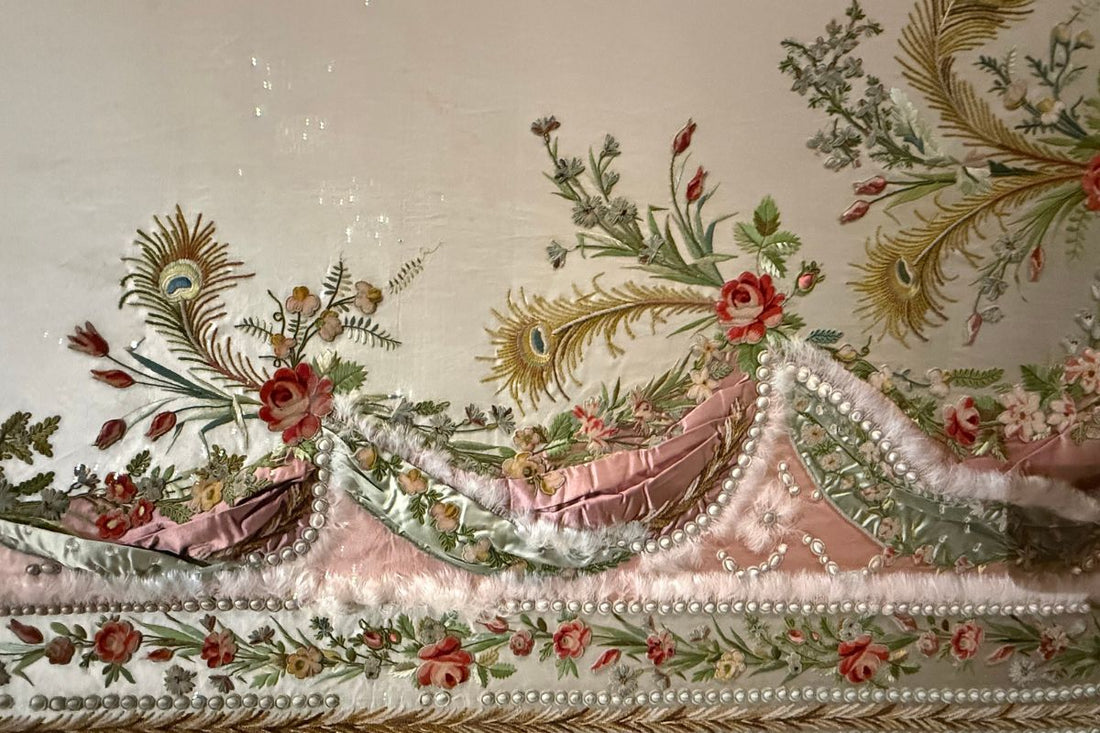 Close-up of an elaborately embroidered 18th century bodice with silk roses, peacock feathers, and pearl trim — Marie Antoinette exhibition, London