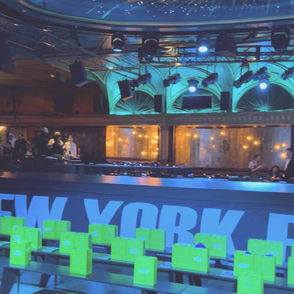 A New York Fashion Week venue with rows of green seating before the show.