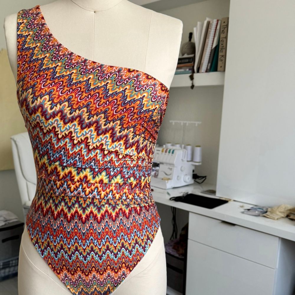 A model on the beach in a handmade one-shoulder chevron-print swimsuit.