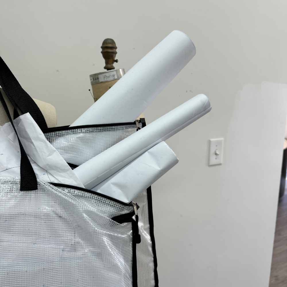 Rolls of pattern paper leaning against a dress form in a home sewing studio.