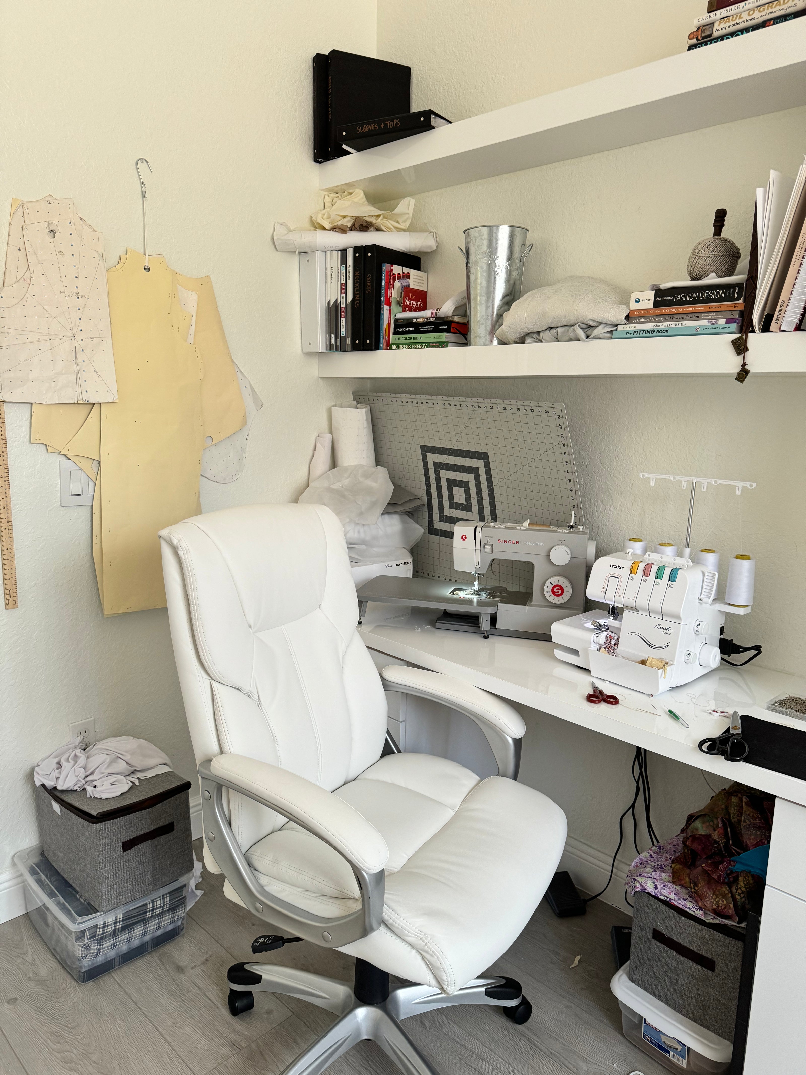 Home sewing room with a white chair, sewing machine, and shelves.