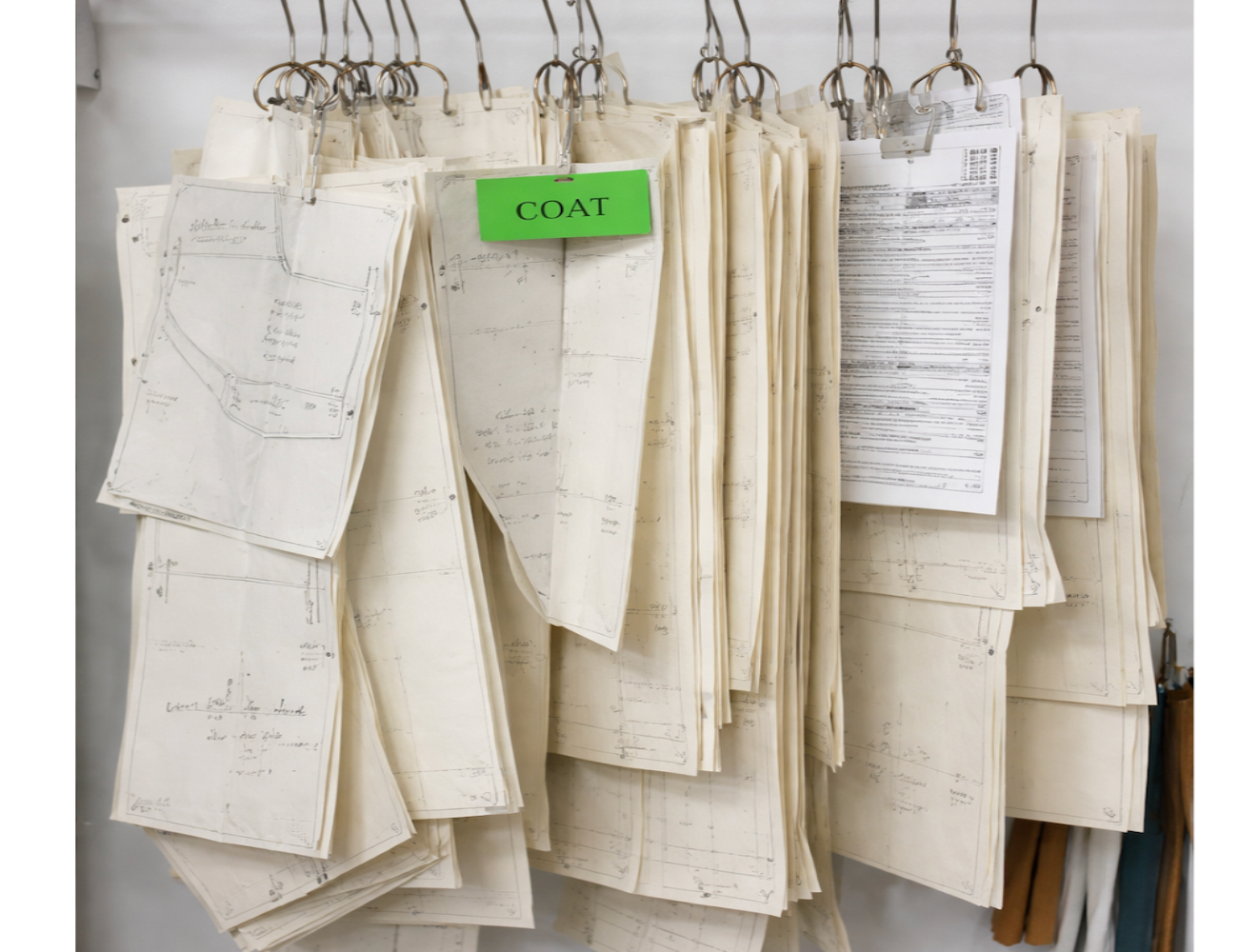 Professional pattern making workspace with drafted coat pattern pieces, tailor's notes, and technical specifications for garment production