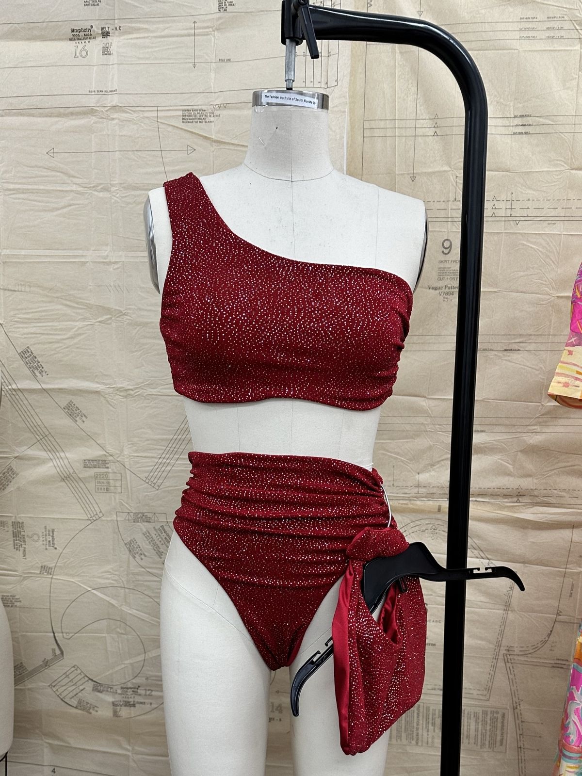 After Stilettos Ember Line one-shoulder sequin bikini set on dress form showing asymmetric top and ruched high-waist bottom with tie detail
