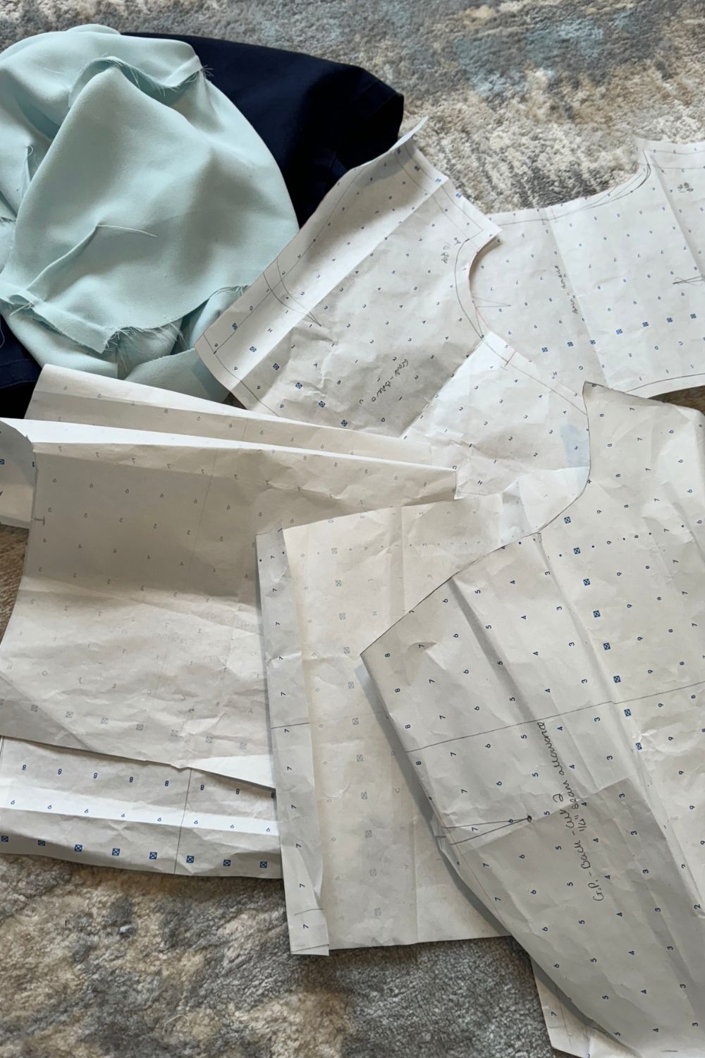 Pattern cutting in progress with teal fabric pieces and sewing notions on the atelier table — After Stilettos behind the seams