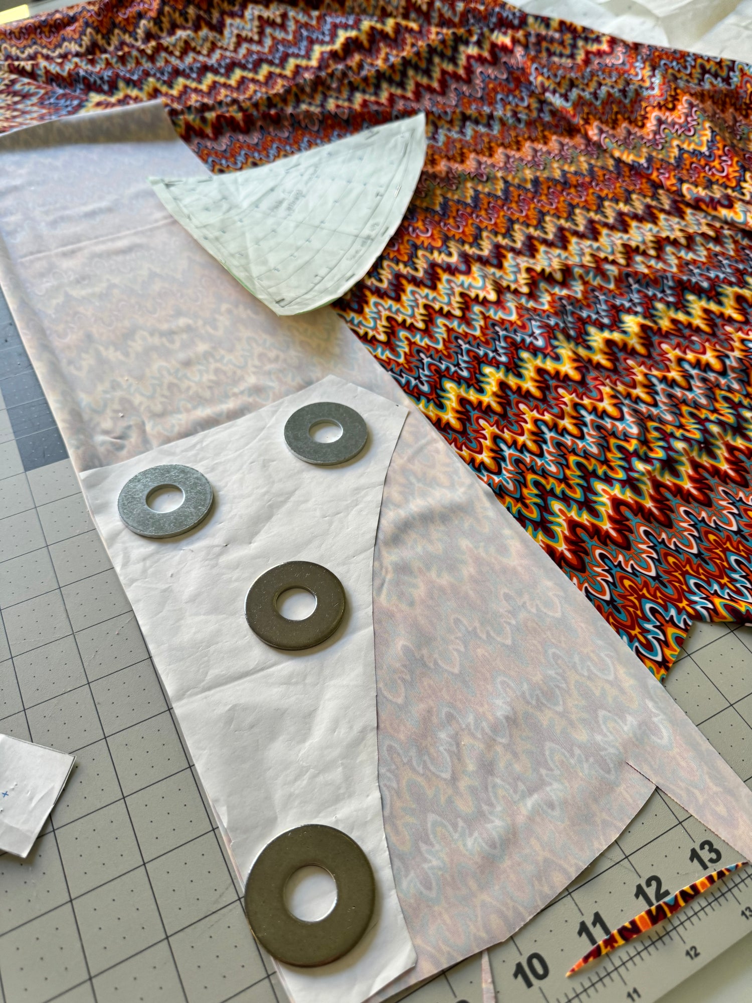 Fabric with cut-out shapes and washers on a cutting mat