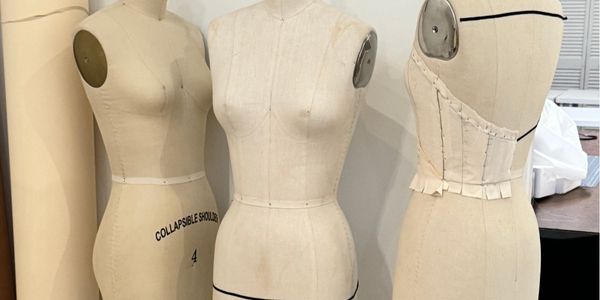 Dress forms and garments in progress representing sewing, construction, and the craft of making clothing.
