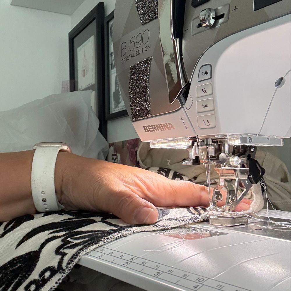 Close-up of hands threading a needle over a pin cushion — After Stilettos fit and alterations
