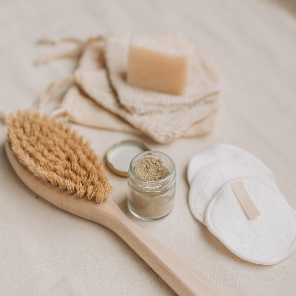 Foot care and comfort essentials including a wooden brush, reusable cotton pads, and natural self-care items arranged on a neutral surface