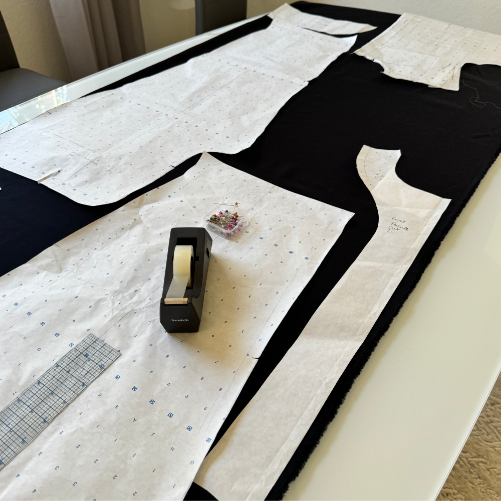 Process and practice shown through pattern pieces laid on fabric with measuring tools and pins during garment construction