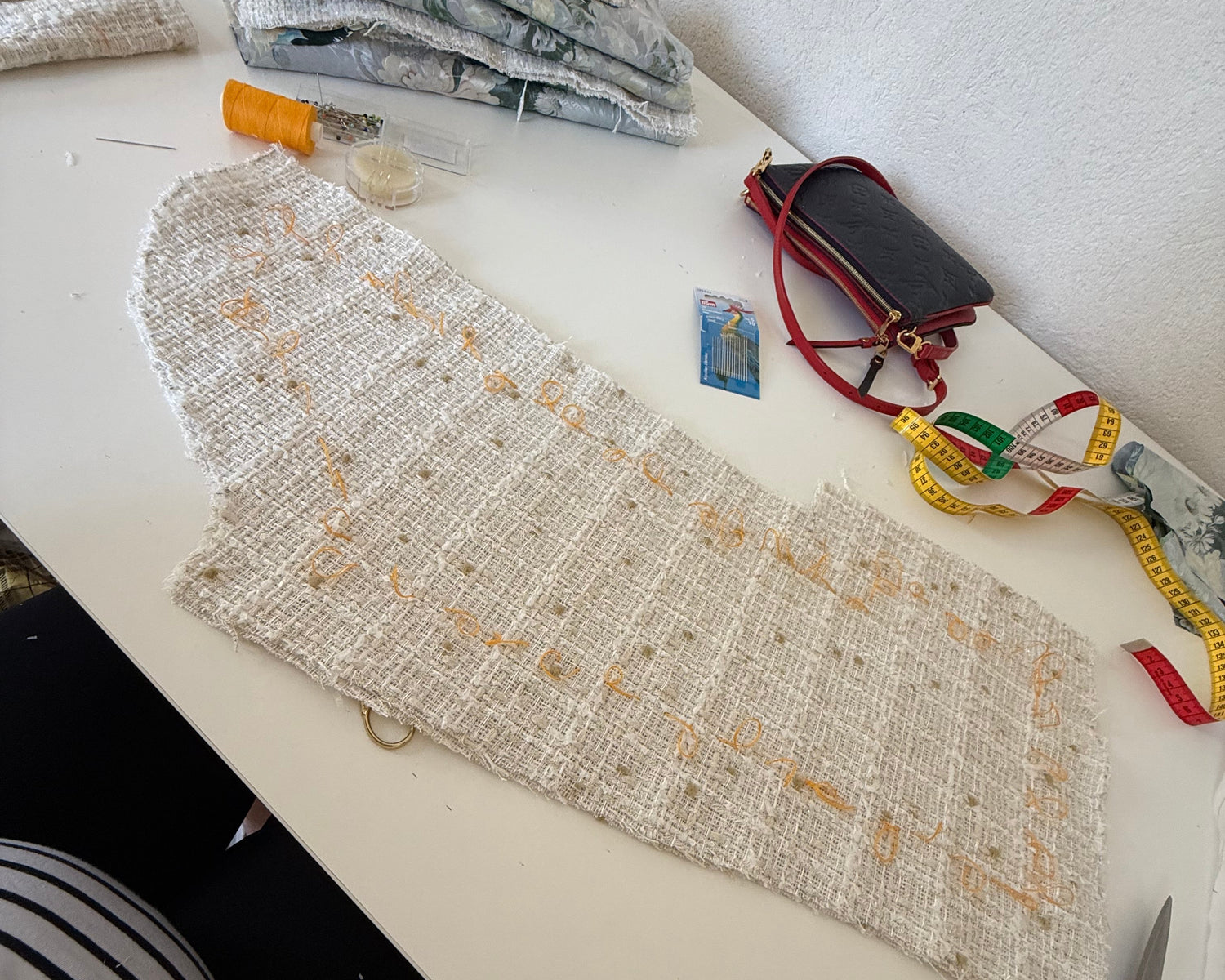 Sewing workspace with measuring tape scissors and beaded fabric showing garment construction process